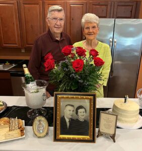 Arabella of Athens | Resident couple poses in front of flowers and an old portrait for their anniversary