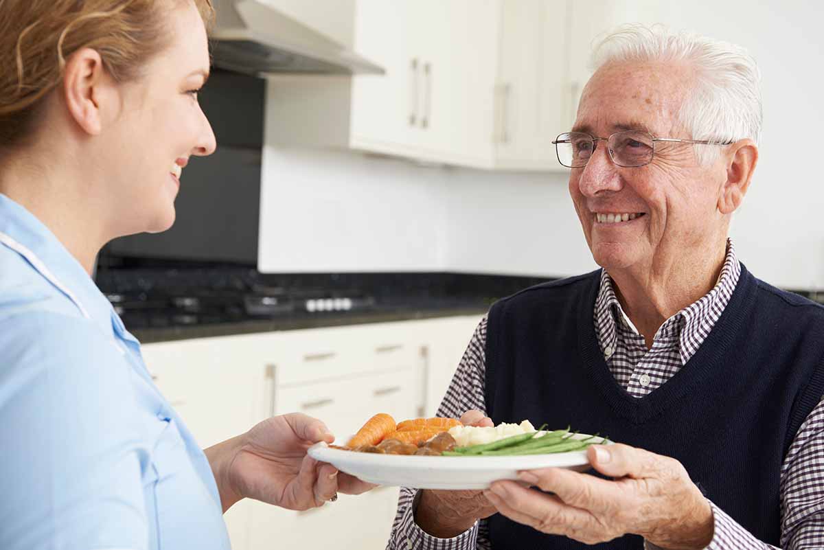 Ledgestone | Carer Serving Lunch To Senior Man