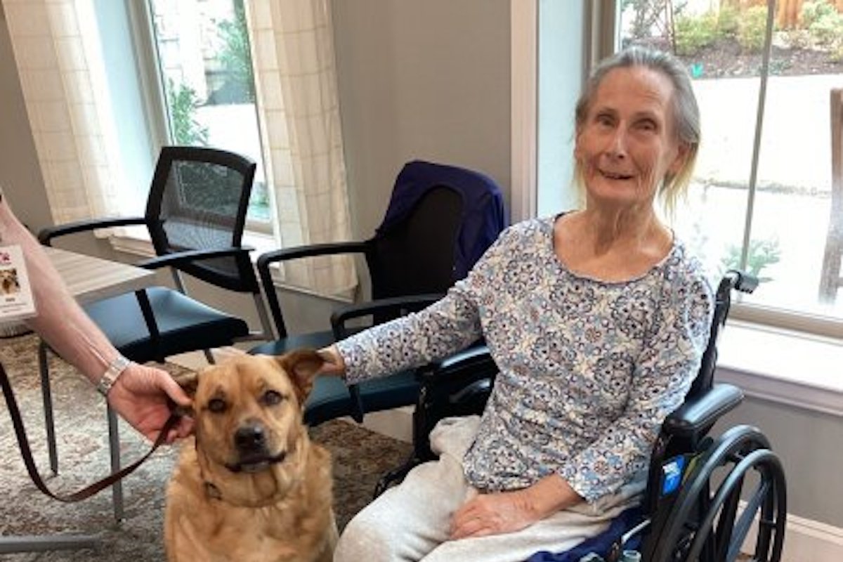 StoneCreek of Copperfield | Smiling memory care resident petting a dog