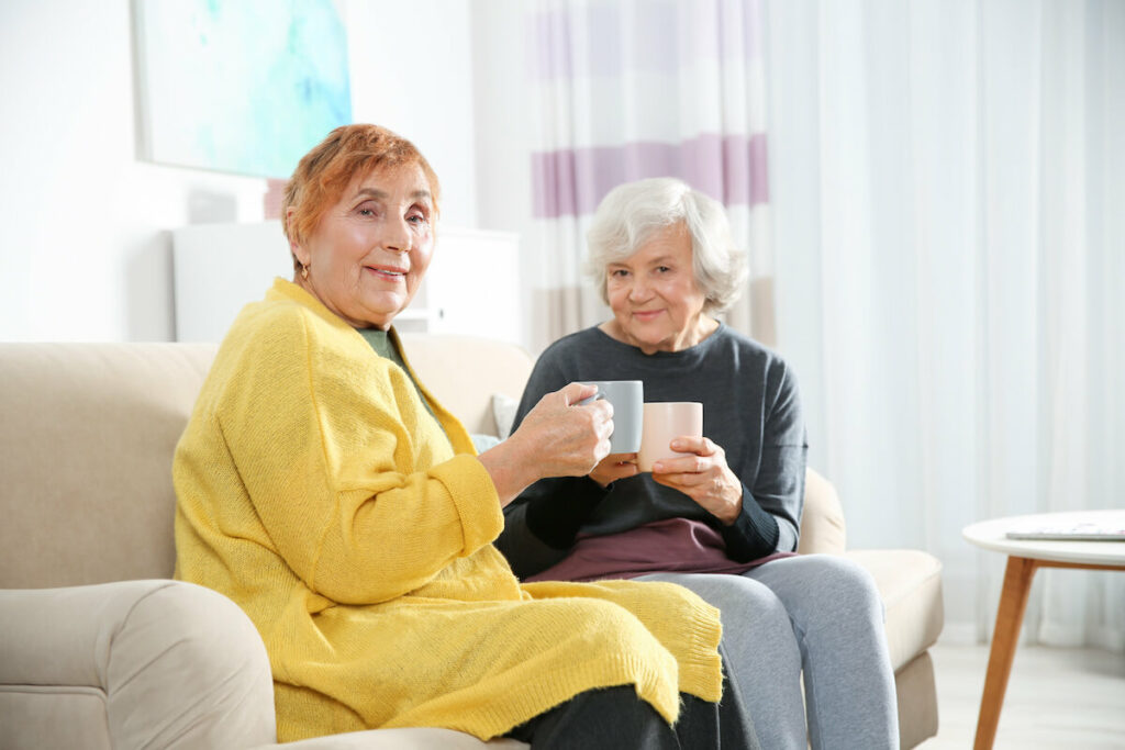 StoneCreek of Flying Horse | Happy senior women sitting on couch drinking coffee