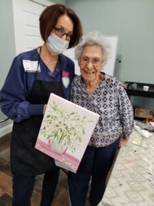 The Brooks of Cibolo | Delia holding up her painting with an associate