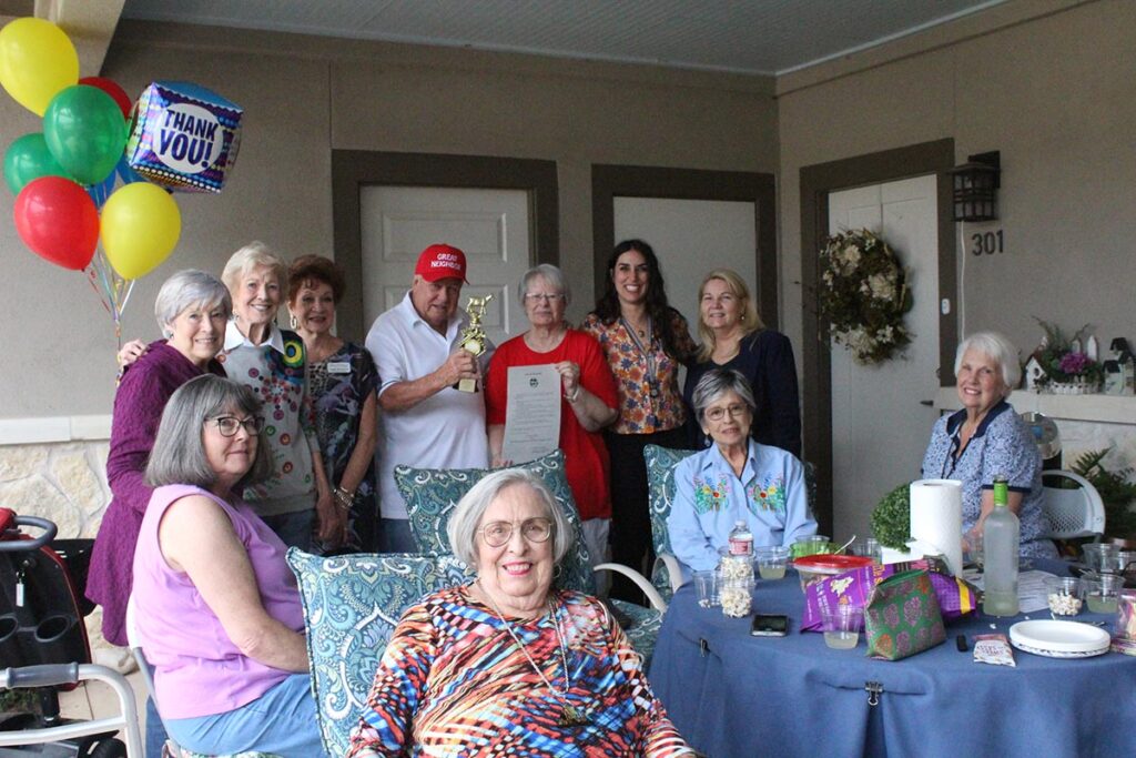 Alexis Pointe of Wimberley | Senior resident, Jack Roach posing with friends and holding up trophy