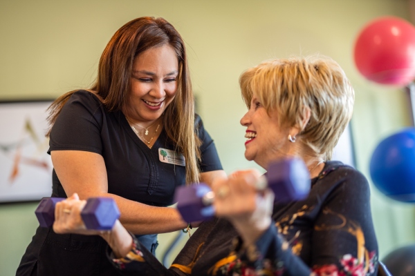 Civitas Senior Living | Senior with caregiver lifting weights