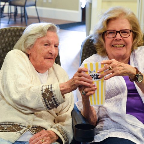 Arabella of Athens | Senior women sharing some popcorn and smiling