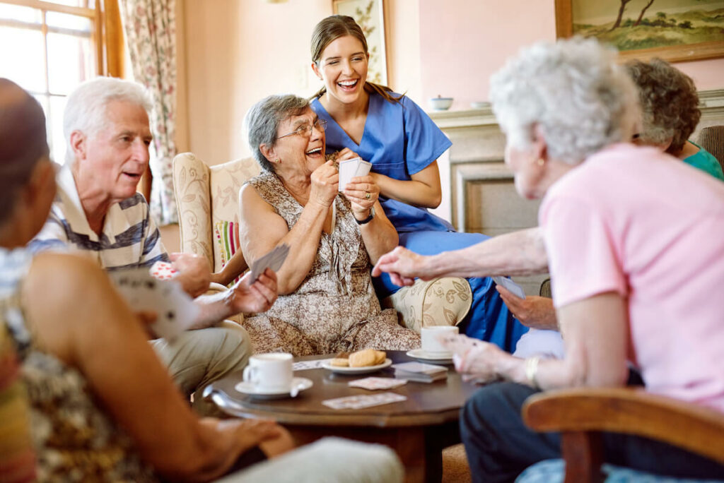 Arabella of Kilgore | A group of happy seniors playing a game of cards, while their caretaker happily watches