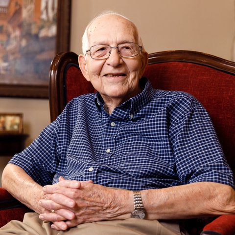 Arabella of Longview | Senior man smiling and sitting in a chair