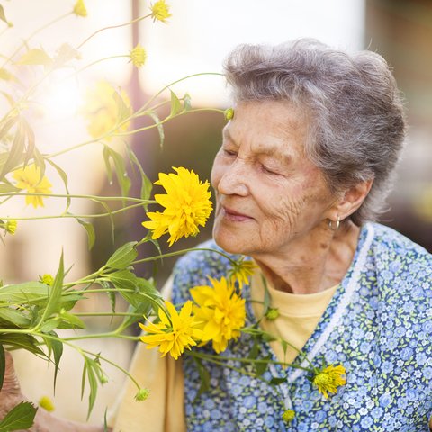 Arabella of Red Oak | Senior woman smelling yellow flowers