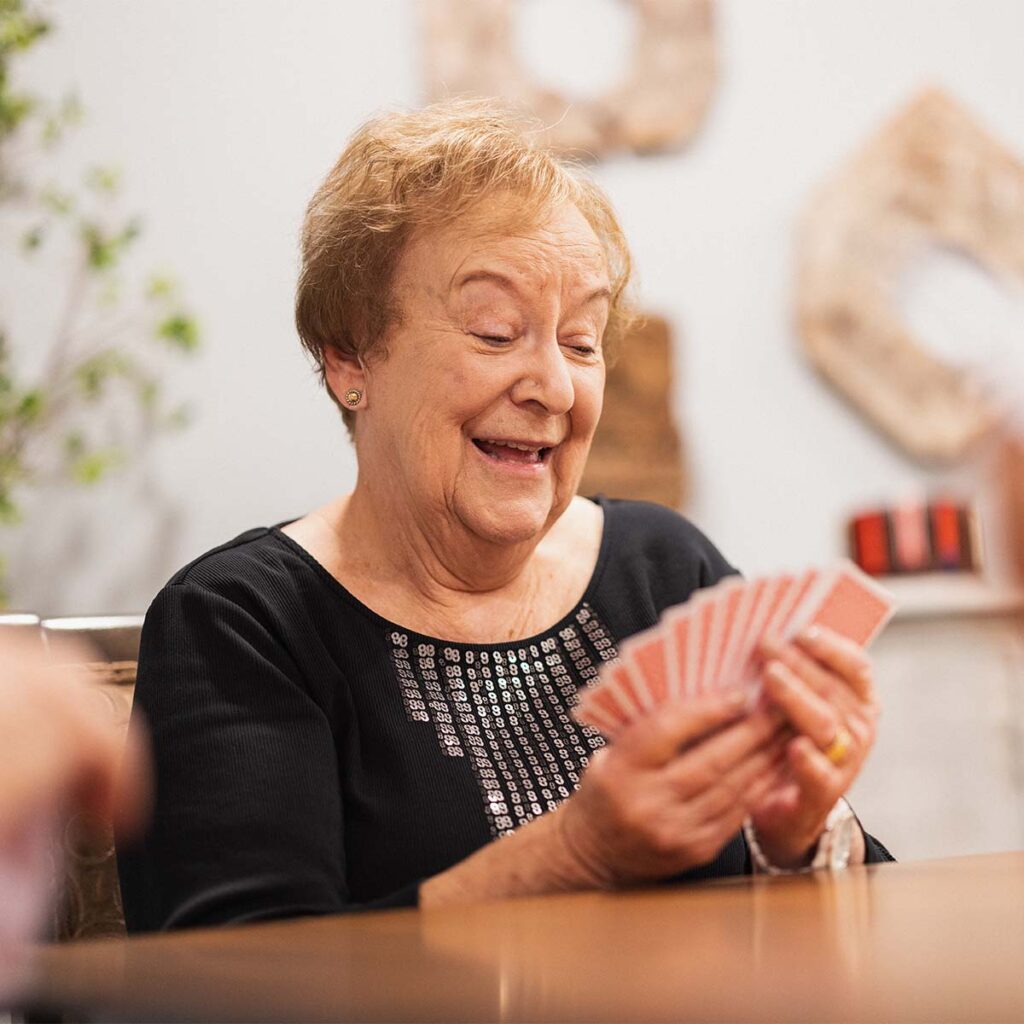 Arabella of Red Oak | Senior woman playing cards and smiling