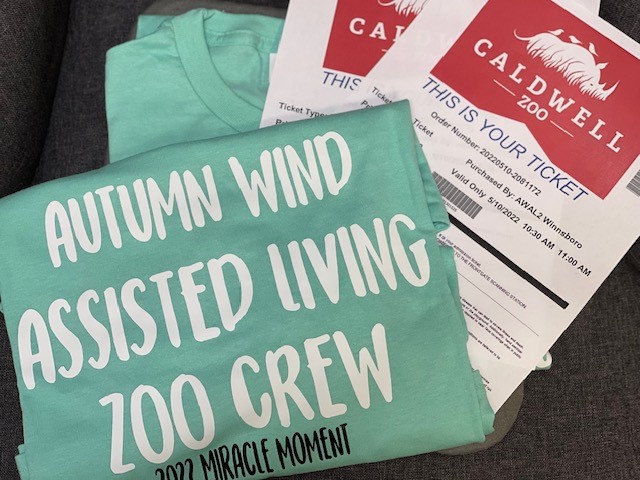 Folded tshirt with text that says "autumn wind Assisted Living zoo crew"