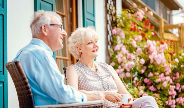 Autumn Wind | Senior couple enjoying their coffee on porch in front of their house