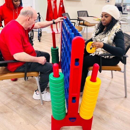 Cambridge Court | Senior playing large connect four game in activity room