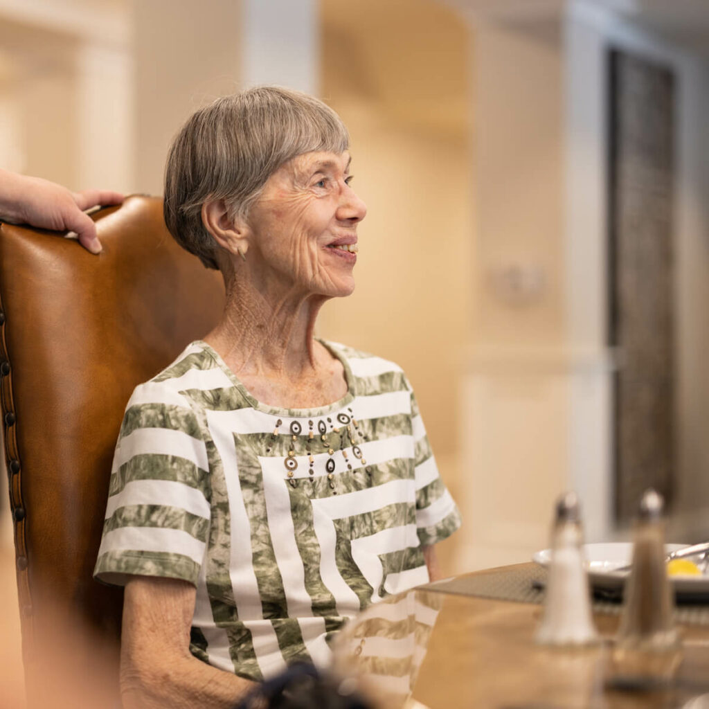 Cambridge Court | Senior woman smiling at table in dining hall
