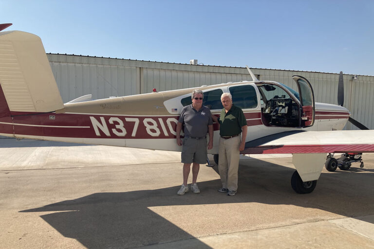 Dancing River | Senior resident, Bob Hatfield, standing next to a small plane