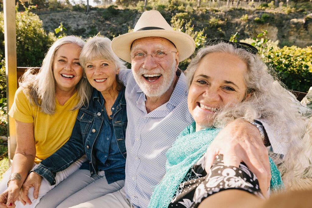 Double Creek | Senior friends sitting on a bench smiling for a selfie