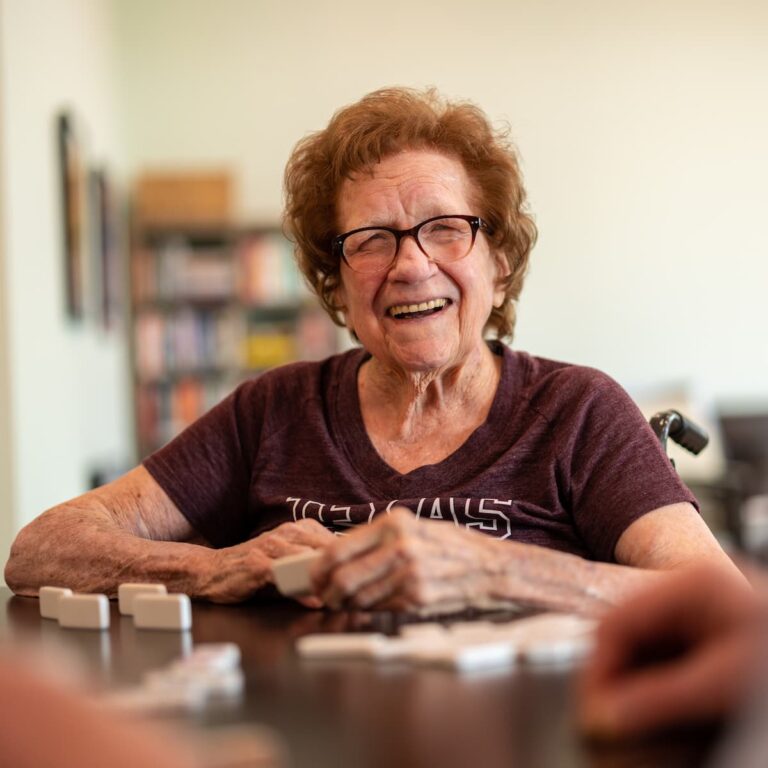Double Creek | Senior woman playing dominoes with friends