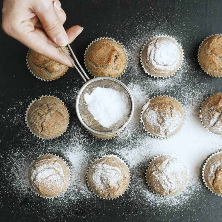 Harvest of Aledo | Baker sprinkling powdered sugar over cupcakes