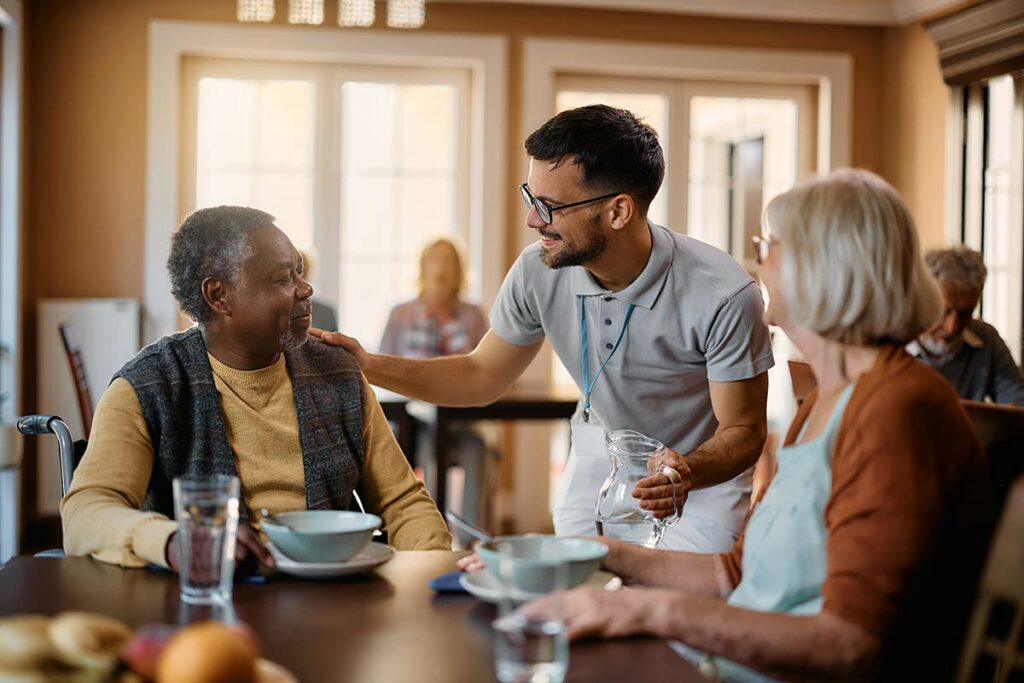 Harvest of Roanoke | Seniors sitting at table with caregiver