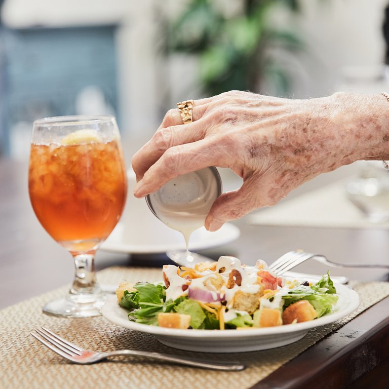 Ledgestone Senior Living | Senior adding dressing to salad