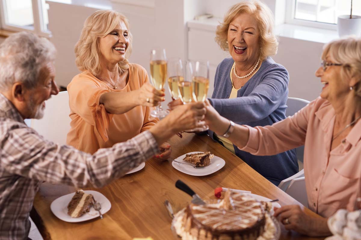 Ledgestone Senior Living | Happy mature friends celebrating Birthday and toasting with Champagne.