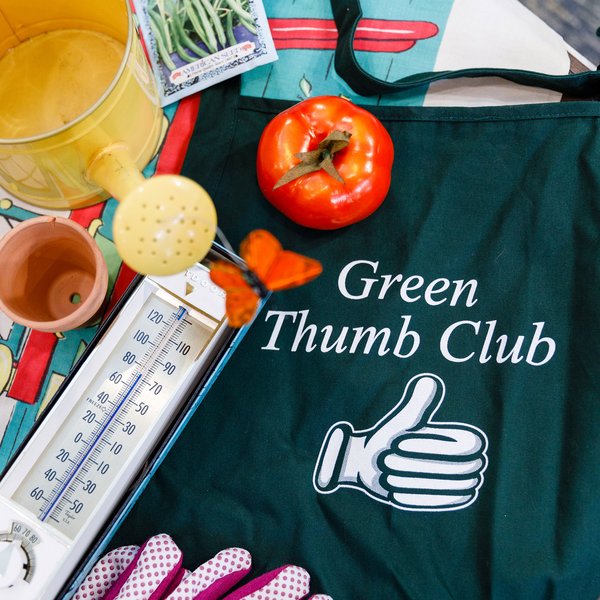 Legacy Oaks of Midlothian | Green Thumb Club apron next laying down surrounded by a tomato, watering pot, thermometer, and n empty plant pot