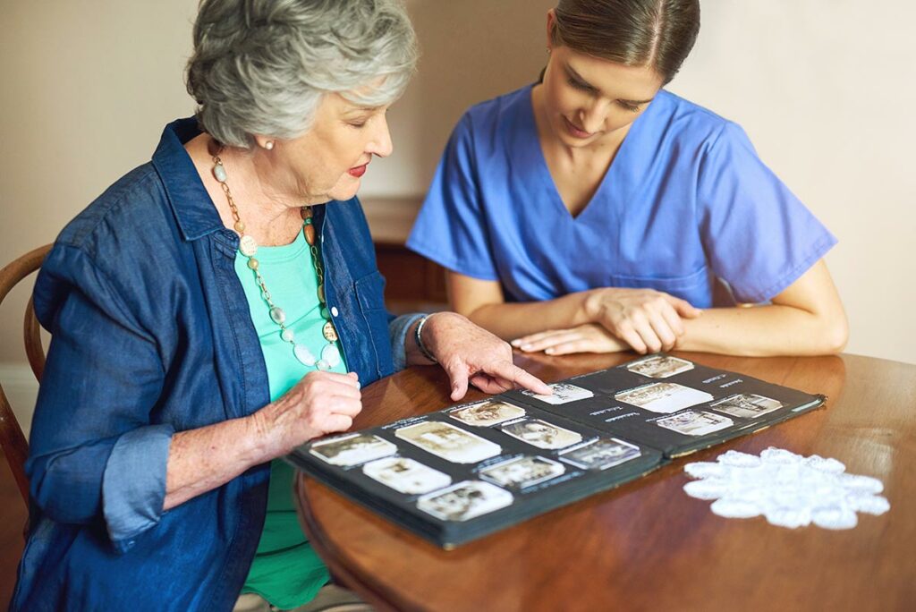 StoneCreek of Copperfield | Senior woman looking at photo album with caregiver