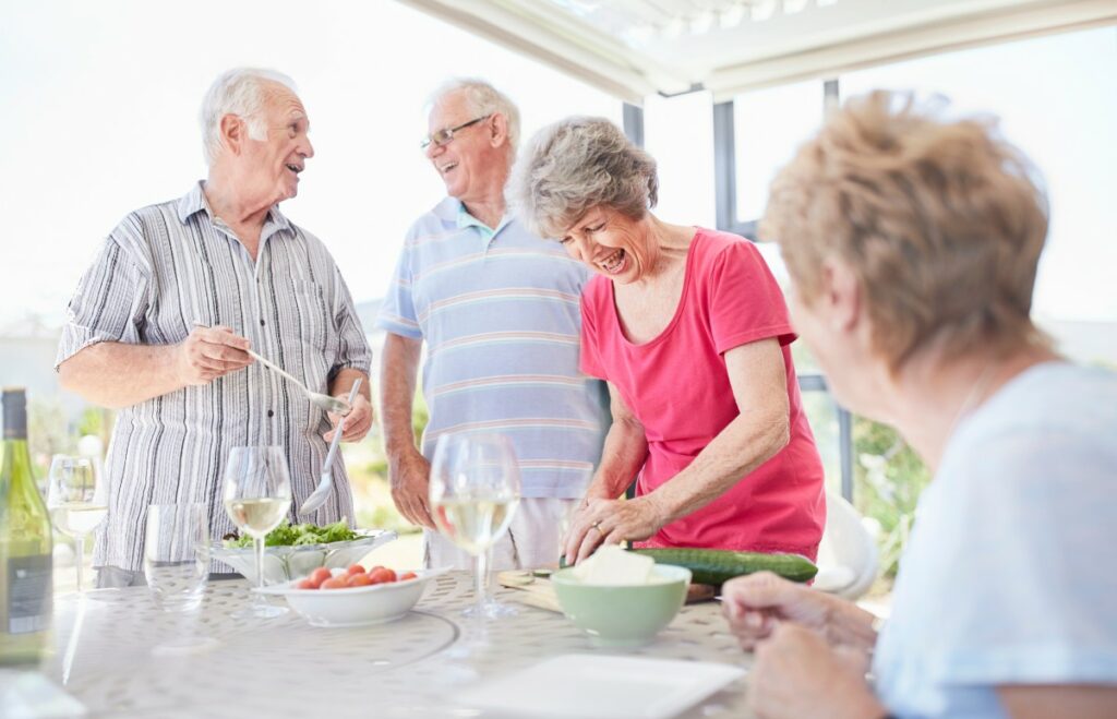 StoneCreek of Copperfield | Happy group of seniors preparing food and socializing