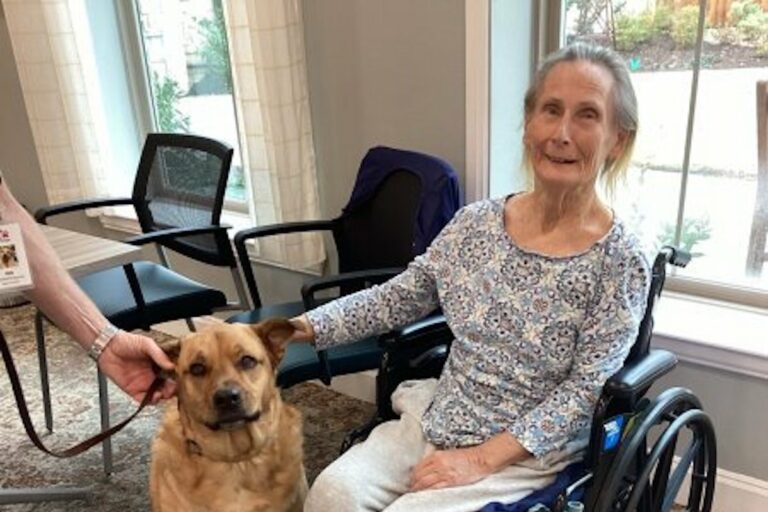 StoneCreek of Copperfield | Smiling memory care resident petting a dog