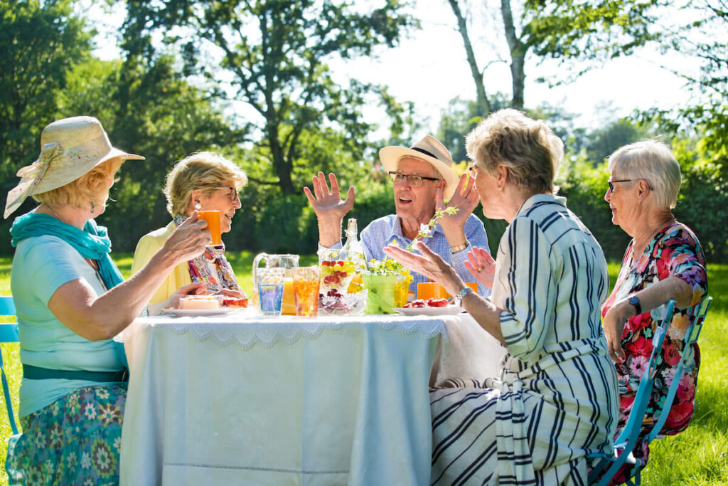 Tech Ridge Oaks | Senior friends having picnick with coffee and cake outdoors in sunshine