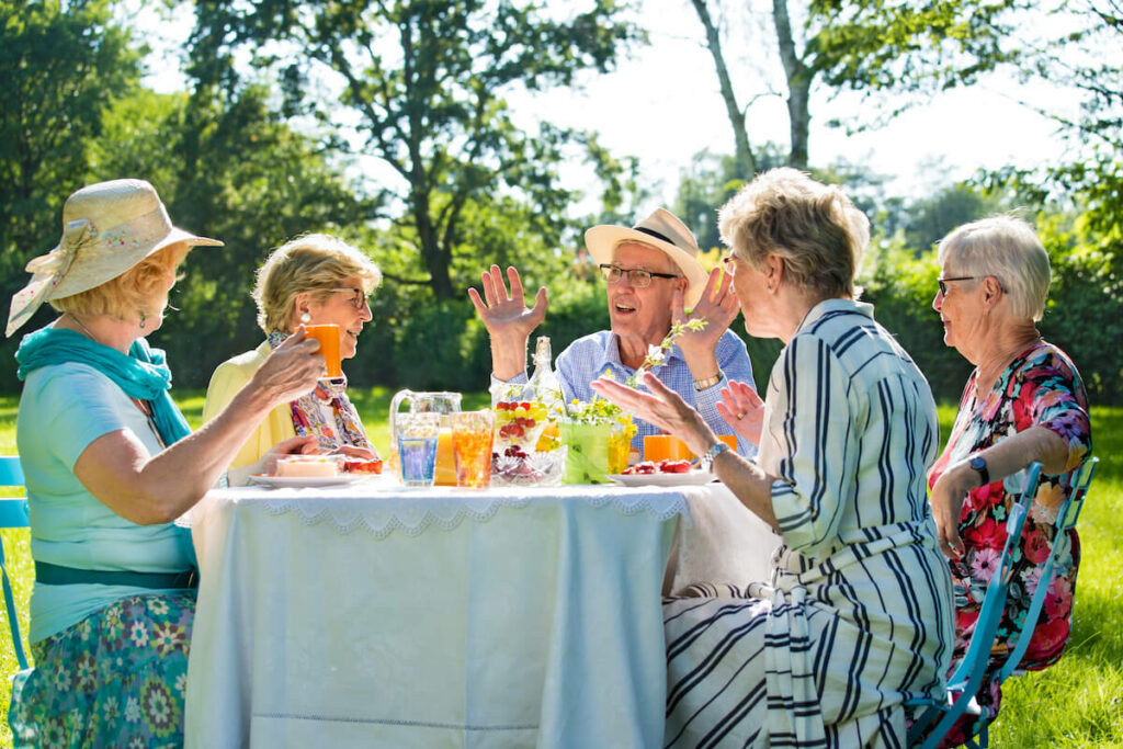 Tech Ridge Oaks | Senior friends having picnic with coffee and cake outdoors in sunshine