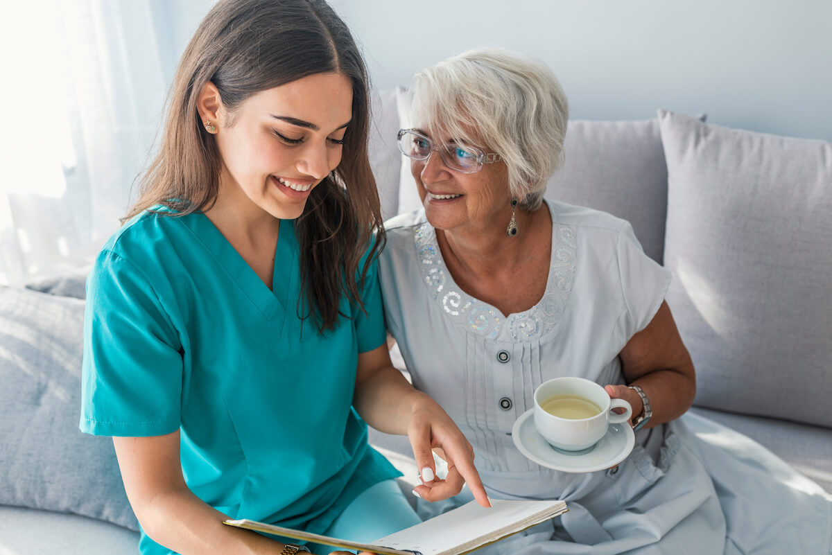 Tech Ridge Oaks | Happy senior with caregiver reading a book