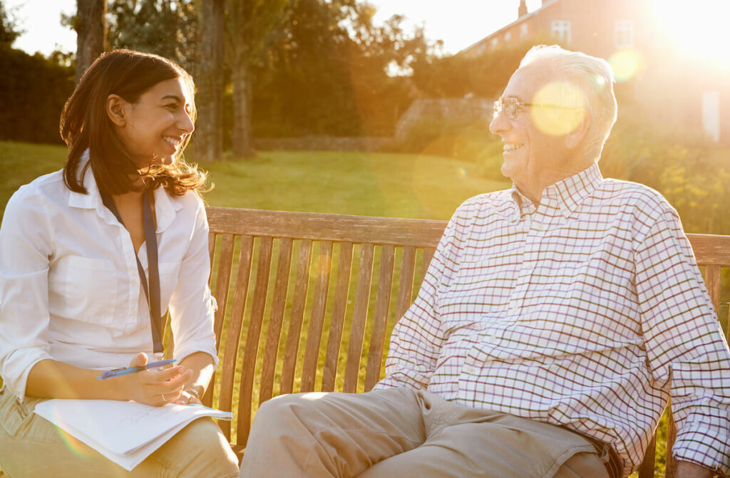 The Grand | Seniro man talking to caregiver on a bench outside