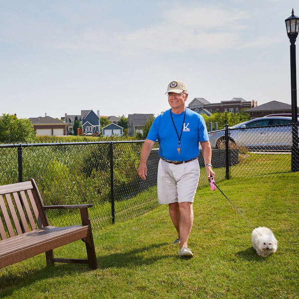 The Grand | Senior man walking his dog next to a bench