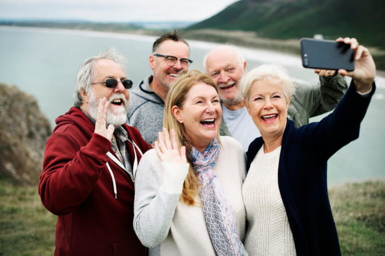 The Grand | Group of happy seniors taking a selfie by the water