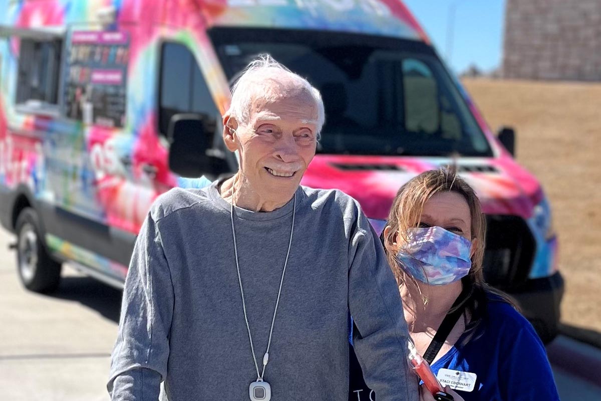 The Grandview of Chisholm Trail | Senior man, Ted Brewer, outside with a woman in a mask