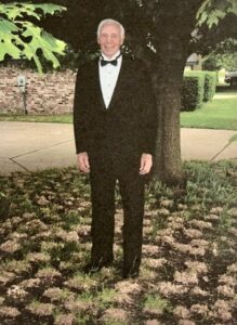 The Grandview of Chisholm Trail | Senior man, Ted Brewer, wearing a suit and standing in front of a tree