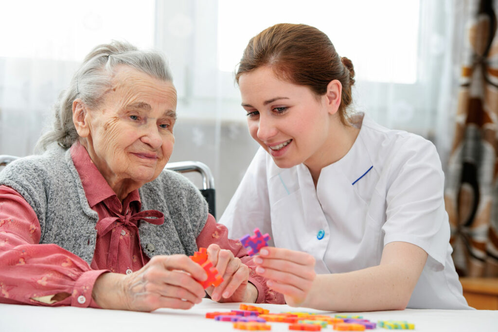 The Ridglea Senior Living | Seniors and caregiver doing a puzzle to help with memory care