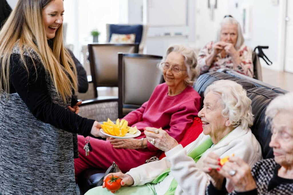 The Ridglea | Senior woman grabbing orange slices from caretaker