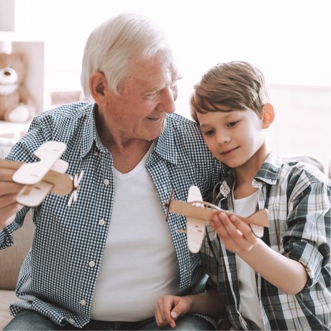 Civitas Senior Living | Senior and grandkid playing with wooden airplanes