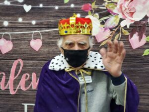 Civitas Senior Living | Senior waving hi and wearing a king's outfit