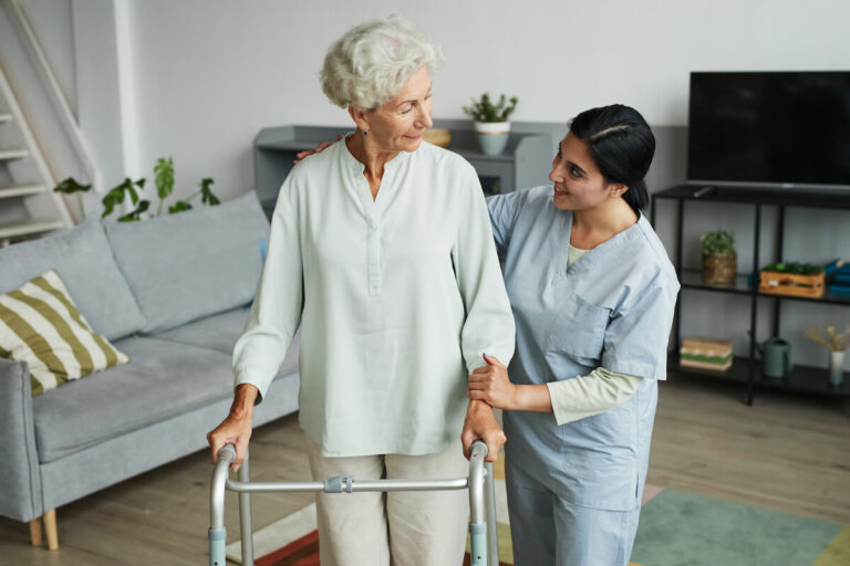 Ariel Pointe of Sachse | Senior woman using a walker and receiving assistance from her caregiver