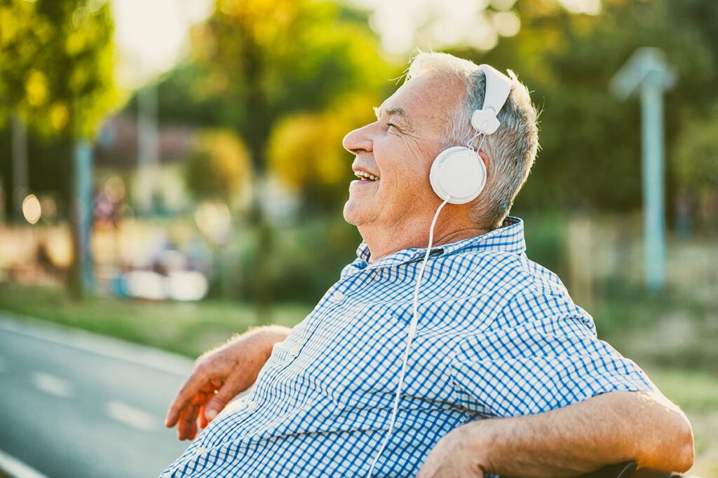 The Grandview of Chisholm | Senior man listening to music on a park bench