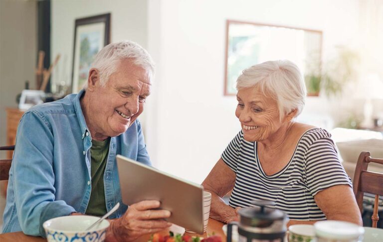 StoneCreek of Flying Horse | Colorado memory care facilities | Senior couple looking at their tablet and smiling