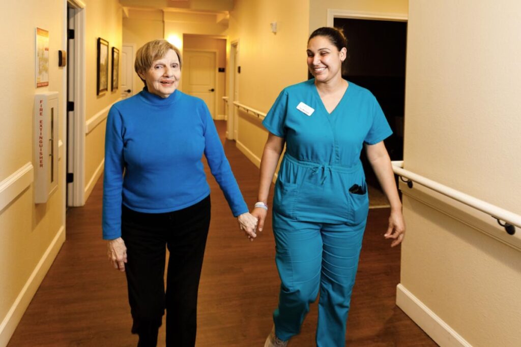 Senior walking with associate in community hallway