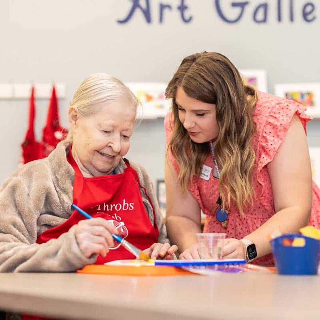 Senior painting with caregiver