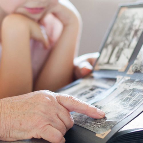 Ledgestone Senior Living | Senior pointing to photo album with granddaughter