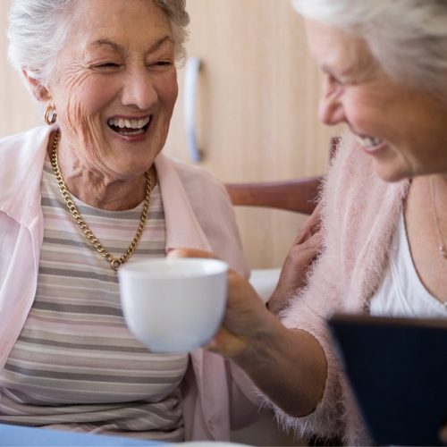Clear Fork | Senior women laughing while drinking tea and using tablet