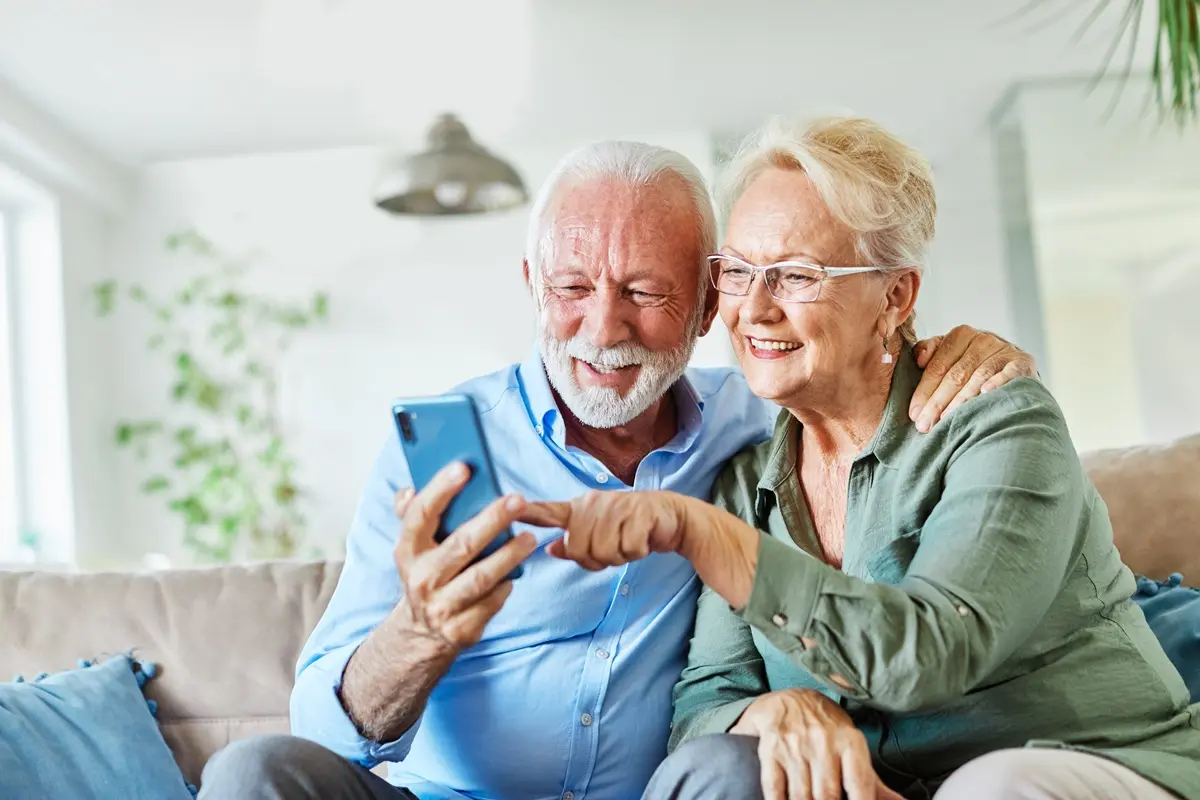 Portrait of an elderly senior couple using a mobile phone at home